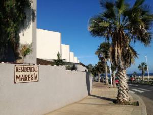 a sign on a wall next to a palm tree at Duplex in quiet zone, next to sea, fast WiFi in El Médano