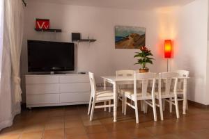 a dining room with a white table and a tv at Duplex in quiet zone, next to sea, fast WiFi in El Médano
