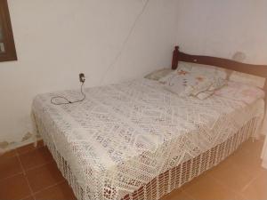 um quarto com uma cama com uma colcha branca em Aconchego em Caraguatatuba