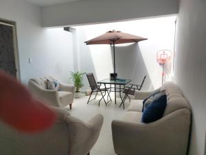 - un salon avec deux canapés et une table avec un parasol dans l'établissement Departamento de playa amoblado, à Cerro Azul