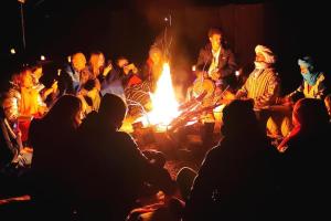 Eine Gruppe von Menschen, die um ein Feuer herum sitzen in der Unterkunft Mirdane Camp in Merzouga