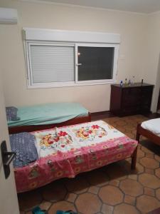 um quarto com 2 camas e uma janela em Mansão Mar casado no Guarujá
