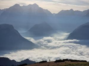 una persona parada en la cima de una montaña con nubes en Comfy mountain nest, en Mojstrana