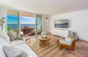 een woonkamer met een bank en een tafel bij Blue Dolphin: An Oceanfront Malibu Sanctuary in Malibu