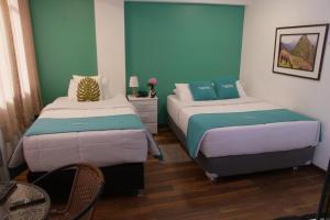 2 camas en una habitación con paredes azules y verdes en MATARA GREENS HOTEL, en Cusco