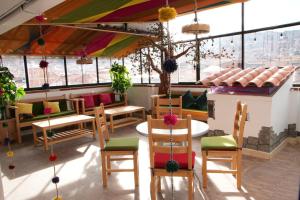 a restaurant with tables and chairs and windows at MATARA GREENS HOTEL in Cusco