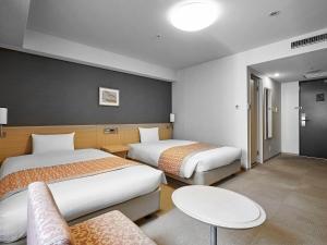 a hotel room with two beds and a table at Daiwa Roynet Hotel Hiroshima in Hiroshima