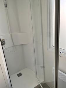 a shower with a glass door next to a window at Mobilhome Luminosa tt équipé 6/8 pers in Les Mathes
