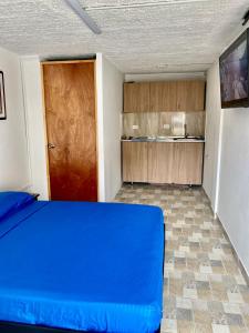 een slaapkamer met een blauw bed en een houten deur bij Hermoso apartamento en San Pablo Guayabal in Medellín