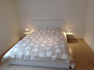 a white bed in a room with two lamps at Le Route 80 in Namur