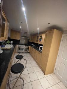 a kitchen with wooden cabinets and two stools in it at Deluxe Room En-suite Free Parking in Seven Kings