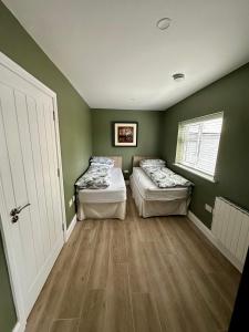 two beds in a room with green walls and wooden floors at Mary cottage at Tonylion house Kilnaleck in Cavan