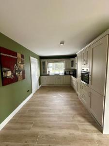 a large kitchen with green walls and white cabinets at Mary cottage at Tonylion house Kilnaleck in Cavan