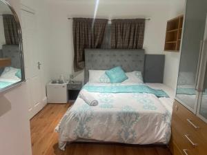 a bedroom with a bed with a blue and white comforter at Double Room En-suite Free Parking in Seven Kings