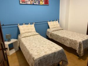 Cette chambre comprend 2 lits et un mur bleu. dans l'établissement La Casita, à Bagheria