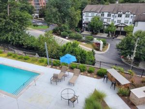 Atlanta Buckhead Cozi في أتلانتا: فناء مع مسبح وكراسي ومظلة زرقاء