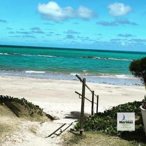 a sign on a beach with the ocean at Apart Hotel Marinas Tamandaré in Tamandaré