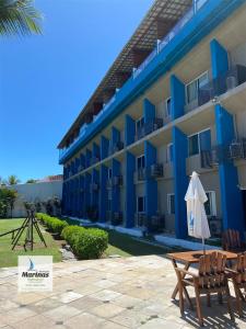 a hotel with a table and chairs and an umbrella at Apart Hotel Marinas Tamandaré in Tamandaré