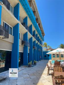 a hotel with blue columns and chairs and a patio at Apart Hotel Marinas Tamandaré in Tamandaré