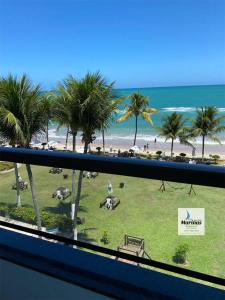 a view of a beach and palm trees from a balcony at Apart Hotel Marinas Tamandaré in Tamandaré