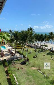a park with a beach with palm trees and chairs at Apart Hotel Marinas Tamandaré in Tamandaré