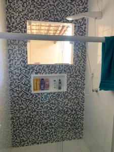 ein Bad mit einer Dusche mit einem Spiegel und einem Fenster in der Unterkunft Casinha da Paz in Aracaju