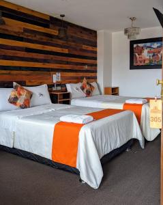 two beds in a hotel room with a wooden wall at Hotel Plaza Central in Ayacucho