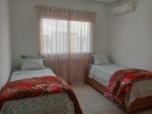 1 dormitorio con 2 camas y ventana en appartement S+2, proche plage en Monastir