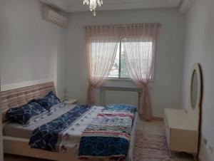 a bedroom with a bed and two windows at appartement S+2, proche plage in Monastir