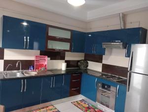 cocina con armarios azules y nevera blanca en appartement S+2, proche plage en Monastir