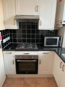 a kitchen with a stove and a microwave at Fully equipped entire flat in Lewisham in London
