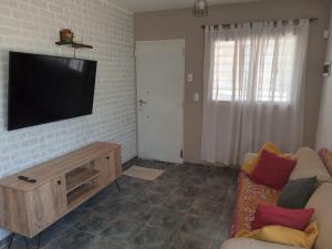 a living room with a flat screen tv on a brick wall at La Casita de Nala in Neuquén