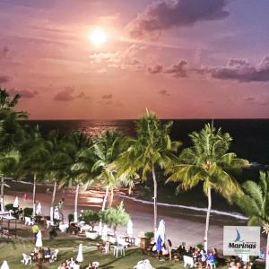 a view of a beach with palm trees at night at Apart Hotel Marinas Tamandaré in Tamandaré