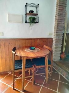 una mesa de madera con sillas y un plato. en Casita del Tejedor, en Frigiliana