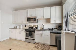 a kitchen with white cabinets and stainless steel appliances at Roomy & Inviting 3BR Chicago Apartment - 53rd St 2E in Chicago