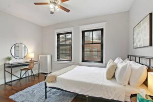 a white bedroom with a bed and a ceiling fan at Roomy & Inviting 3BR Chicago Apartment - 53rd St 2E in Chicago