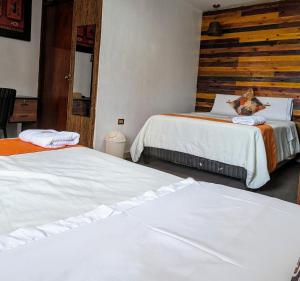 a bedroom with two beds and a wooden wall at Hotel Plaza Central in Ayacucho