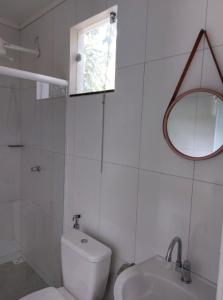 uma casa de banho branca com um WC e um espelho. em Pousada Jardim de Pedras em Pancas