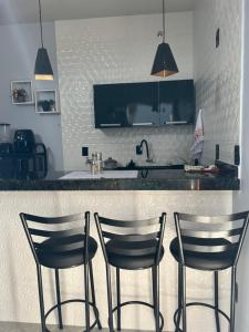 a kitchen with two bar chairs and a counter at Kitnets Cidade de Goiás-Go 02 in Goiás +3 photos