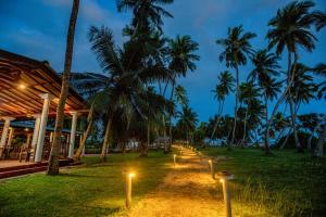 un sentiero con luci di fronte a un edificio con palme di Helios Beach Resort a Tangalle