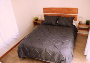 ein Schlafzimmer mit einem Bett mit einer grauen Bettdecke in der Unterkunft Cabaña en la montaña Ilalo - Quito in Quito