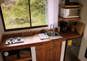 eine Küche mit einer Theke mit einem Waschbecken und einem Fenster in der Unterkunft Cabaña en la montaña Ilalo - Quito in Quito