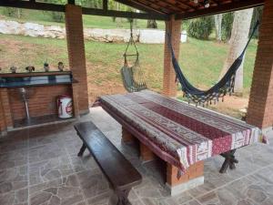 a porch with a bench and hammocks in a yard at Linda chácara em Ibiuna com lago e piscina in Ibiúna