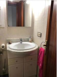 ein Badezimmer mit einem weißen Waschbecken und einem Spiegel in der Unterkunft Habitacion RUSTICA en Palma para una sola persona en casa familiar in Palma de Mallorca