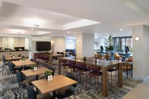 a restaurant with tables and chairs and a tv at Mercure Sydney Manly Warringah in Sydney