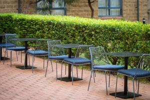 a row of tables and chairs sitting in front of a hedge at Mercure Sydney Manly Warringah in Sydney