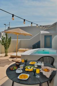 a table with food and drinks on a patio with a pool at Luna Santorini Suites in Pyrgos