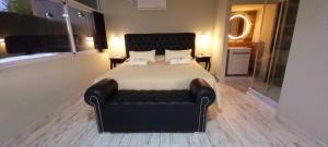 AYRES SUITE في فيلا كارلوس باز: غرفة نوم مع سرير مع أريكة جلدية سوداء