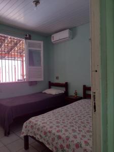 1 dormitorio con 2 camas y ventana en Casa Mosqueiro, en Mosqueiro