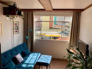 uma sala de estar com um sofá azul e uma janela em Apartamento Teatro Conforto no Centro em Curitiba